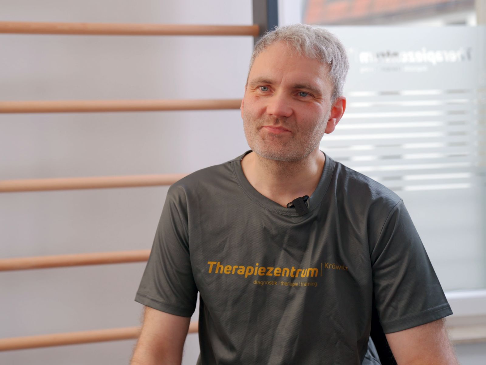 Teammitglied im Praxisshirt vor der Sprossenwand